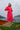 Woman in a red dress standing on a boat with a scenic background in lombok, indonesia.  Wearing broderie anglaise kaftan in cherry red and pure silk headband
