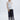 Woman wearing a white top and navy embroidered pants on a white background