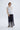 Woman wearing a white top and navy embroidered pants on a white background