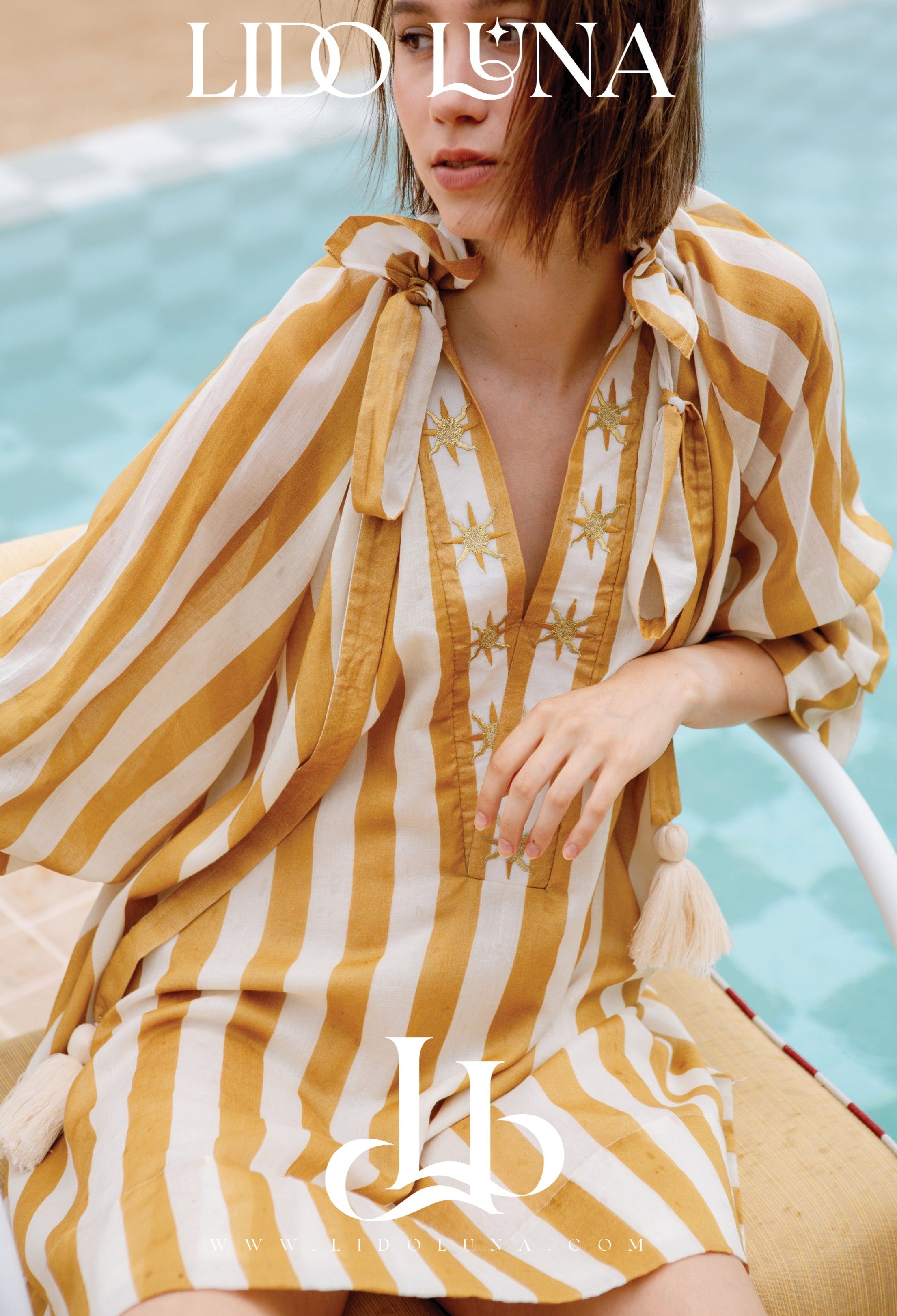 Woman in a yellow and white striped dress by Lido Luna with midcentury vibe and pool background.  Photographed on location at Tanjong Beach Club, Sentosa, Singapore