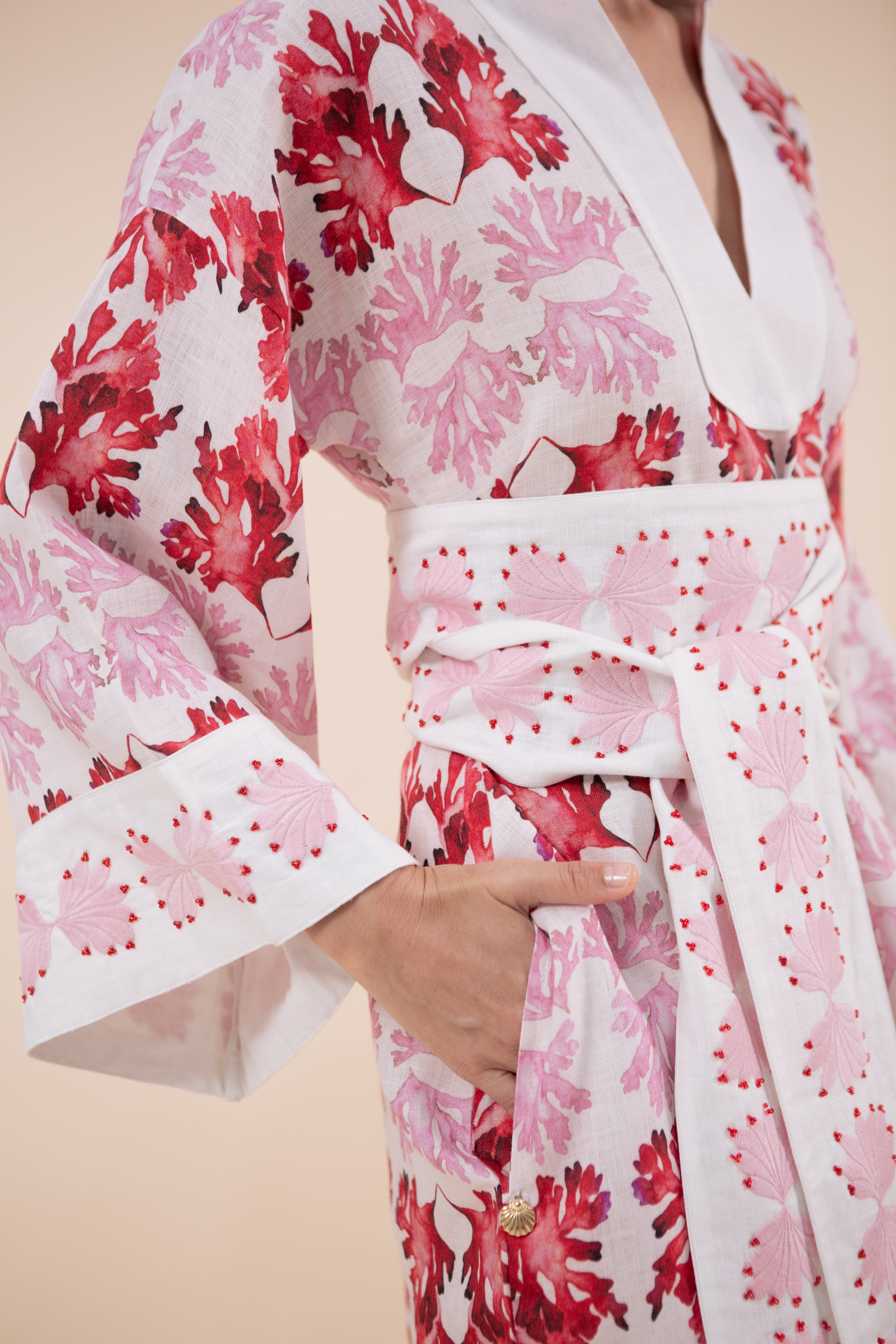 The Nerites dress is a short, popover style in 100% linen in a traditional but modernised kaftan style, with deep placket neckline and wide bell sleeves. Custom print by Fleur Kakasi, with hand embroidery and beading on the cuffs, hem, and double-length belt.