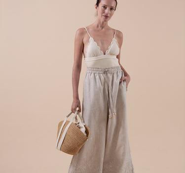 The Nori trousers are an elastic waisted 100% linen pant for a comfortable easy fit, with finishing including real natural pearl and gold plated charms at the end of the belt ties.  Embroidery designed by Fleur Kakasi at the hem. 
