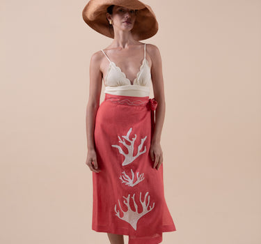 The Poseidon Wrap Skirt is a classic full-wrap style, below knee length, featuring extra long ties, and stunning applique and embroidery details on coral red linen. 
 The contrasting ivory applique features our signature coral motif, with glass pearl beads, and each tie features real natural baroque pearl charms at each end. Design by Fleur Kakasi