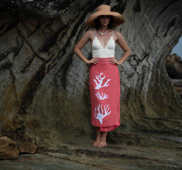 The Poseidon Wrap Skirt is a classic full-wrap style, below knee length, featuring extra long ties, and stunning applique and embroidery details on coral red linen. 
 The contrasting ivory applique features our signature coral motif, with glass pearl beads, and each tie features real natural baroque pearl charms at each end. Design by Fleur Kakasi