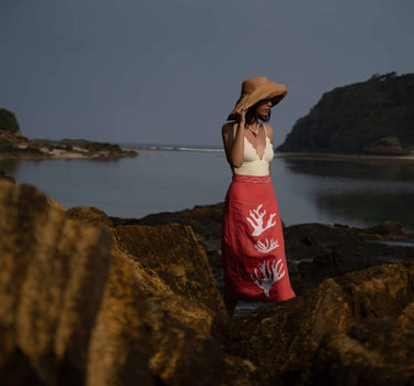 The Poseidon Wrap Skirt is a classic full-wrap style, below knee length, featuring extra long ties, and stunning applique and embroidery details on coral red linen. 
 The contrasting ivory applique features our signature coral motif, with glass pearl beads, and each tie features real natural baroque pearl charms at each end. Design by Fleur Kakasi